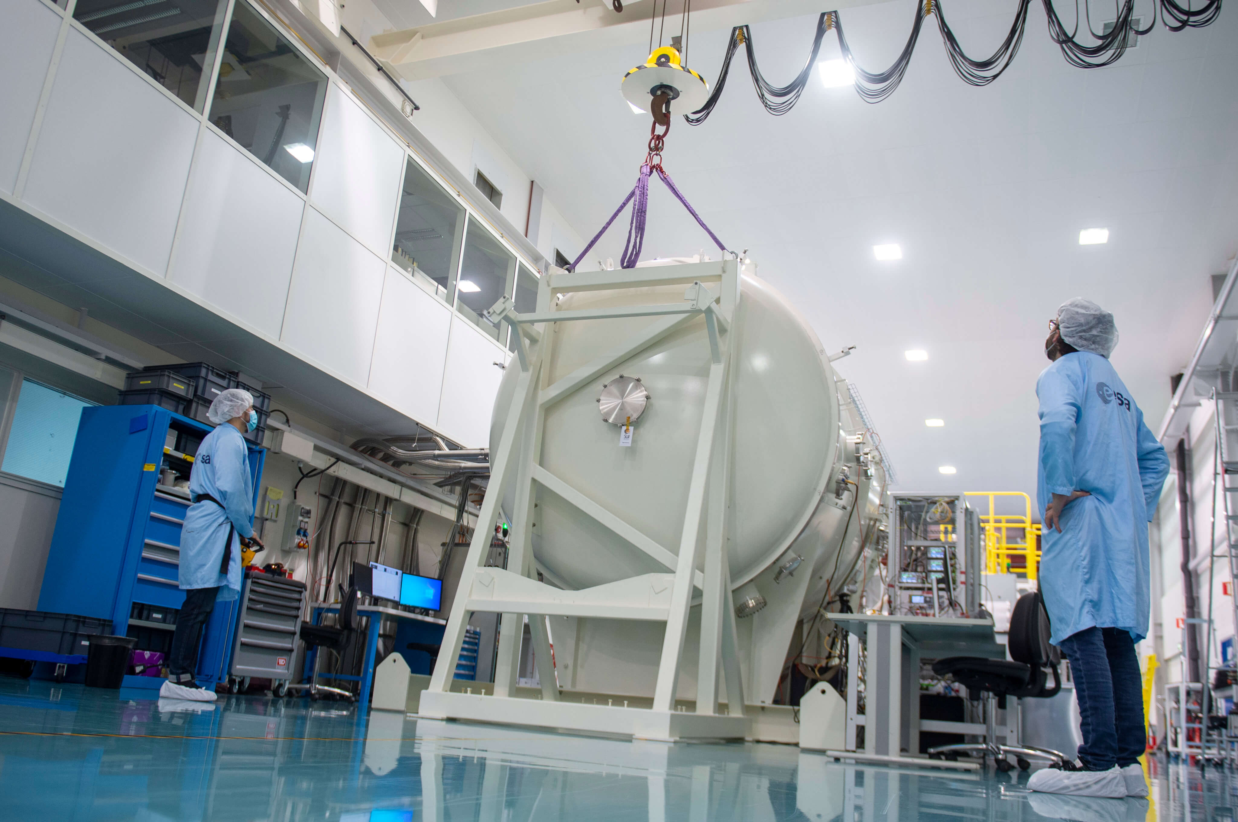 Large metal ends of the LORENTZ test chamber are lifted by crane to seal the chamber and create a vacuum. Each are over 1000 kg. Credits: ESA - G.Porter